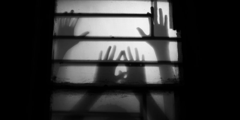 Frauenhände hinter einem Gitter